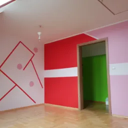 Pokój dziecięcy po malowaniu ścian w odcieniach różu, czerwieni i bieli, z geometrycznymi wzorami i okrągłymi naklejkami, parkiet na podłodze, widoczne okno dachowe.