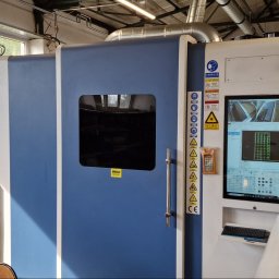 LP KONSTAL - Duża, biało-niebieska maszyna sterowana numerycznie z ekranem wyświetlającym schemat obróbki, widoczne ostrzeżenia i logo producenta OTINUS.