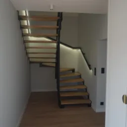 Nowoczesne schody z drewnianymi stopniami i czarną metalową konstrukcją, podświetlone LED, w minimalistycznym wnętrzu z białymi ścianami i drzwiami.