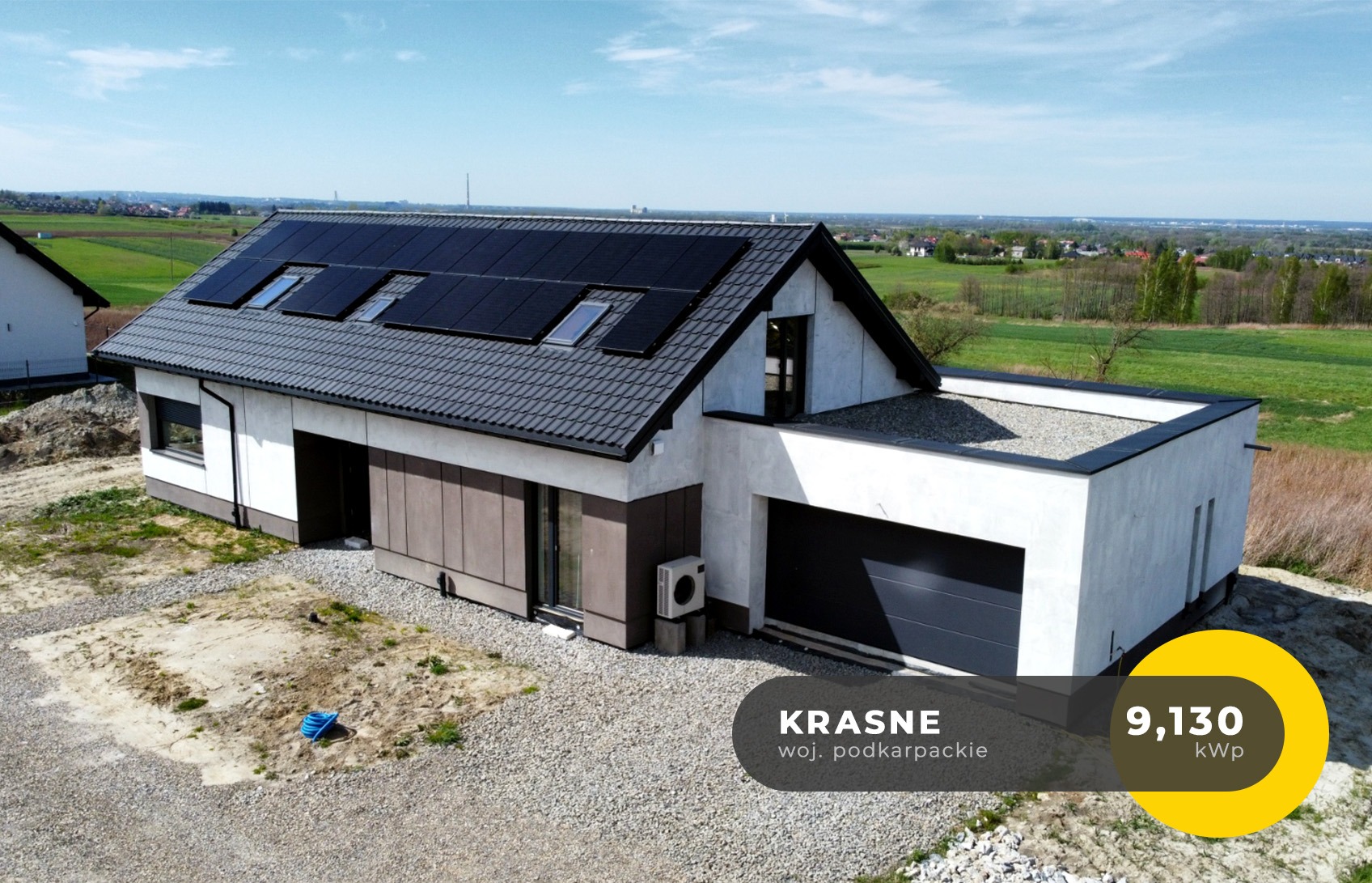 Nowoczesny dom jednorodzinny z panelami słonecznymi na dachu, widok z góry, miejscowość Krasne, woj. podkarpackie, moc instalacji 9,130 kWp, klimatyzator na zewnątrz budynku.