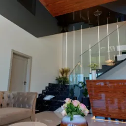 Nowoczesne wnętrze z marmurowymi schodami, szklaną balustradą, drewnianym sufitem i designerskim oświetleniem.