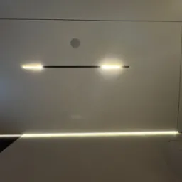 Nowoczesny sufit z wbudowanym oświetleniem LED i głośnikiem. Minimalistyczny design, białe panele, ciepłe światło. Widok od dołu.