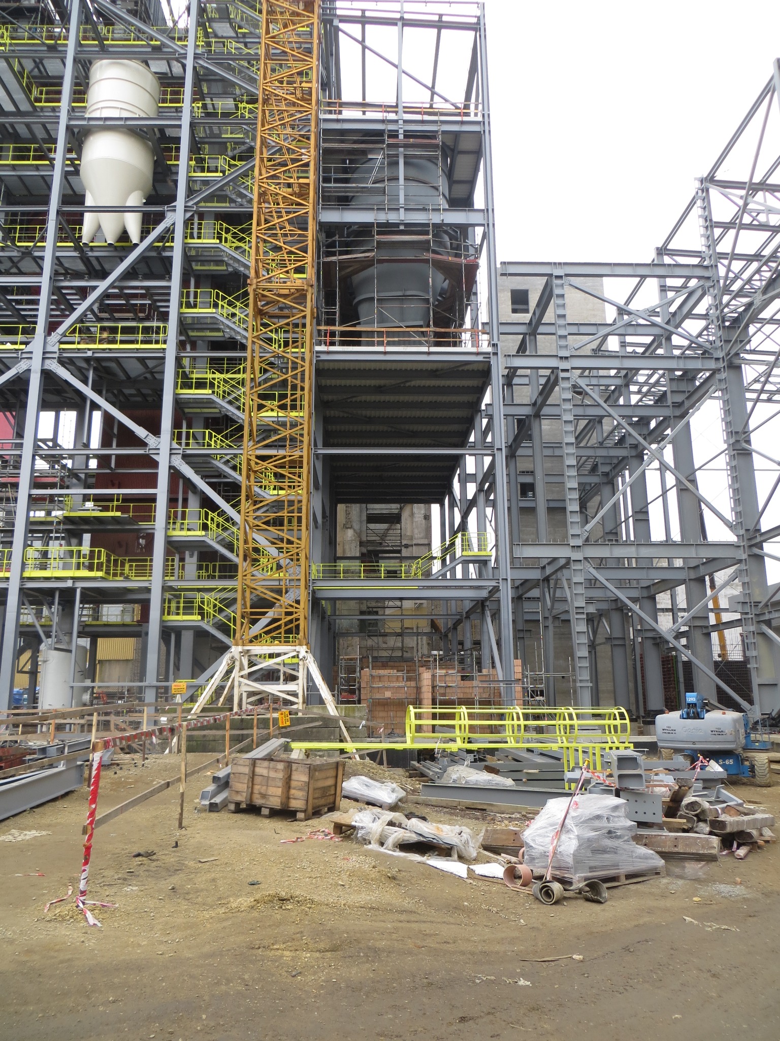 Konstrukcja stalowa hali w trakcie budowy, widoczny dźwig, elementy konstrukcyjne i materiały budowlane na placu budowy w Tychach.