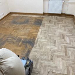 MAXIFLOOR Tomasz Gołaś - Częściowo odnowiony parkiet w jodełkę, widoczna różnica w kolorze przed i po obróbce. W rogu maszyna do cyklinowania z workiem na pył.