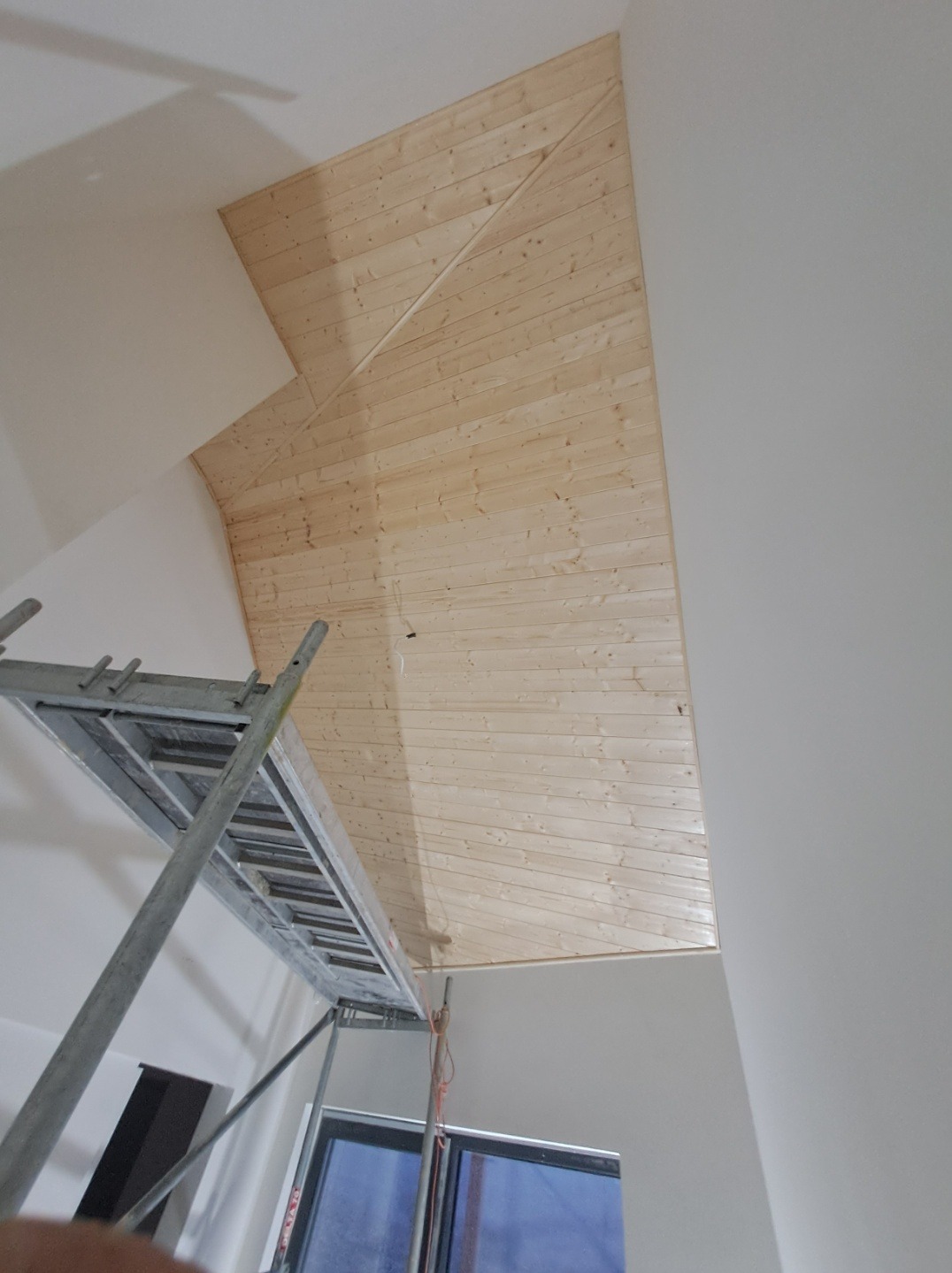 Drewniana boazeria na skośnym suficie poddasza w Olsztynie, widok z dołu ze stojącym rusztowaniem.