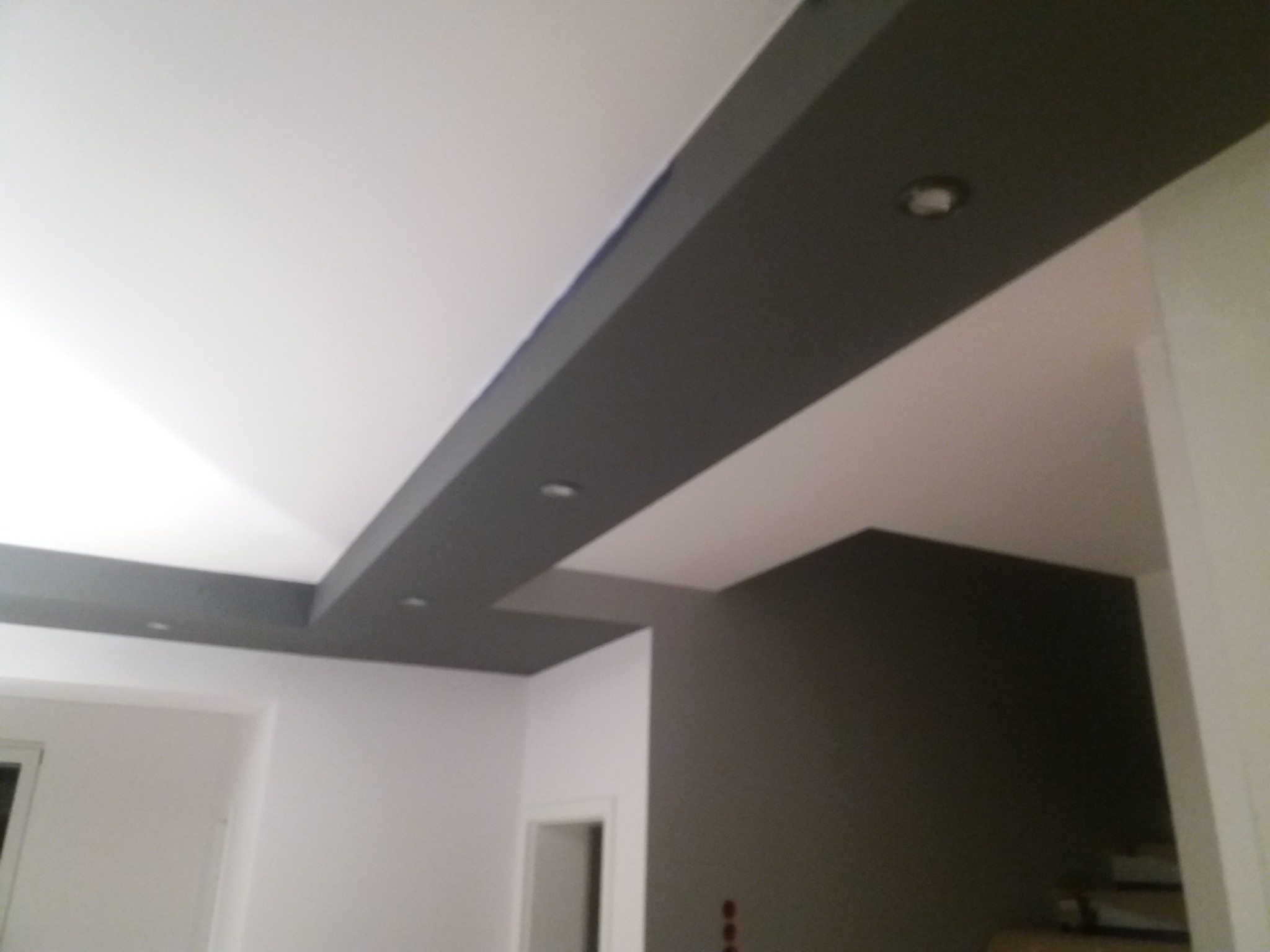 Pomieszczenie po remoncie z pomalowanym sufitem z elementami podwieszanymi w kolorze szarym i zamontowanymi punktowymi źródłami światła