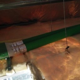 Złota rączka - Damian Krawczyk - Zielony przewód wentylacyjny przymocowany do sufitu z izolacją z wełny mineralnej, widoczne metalowe profile konstrukcyjne.