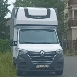 Biały bus Renault Master z nadbudówką Lamico, zaparkowany na brukowanej ulicy, widok z przodu, tablica rejestracyjna PK 3512R.