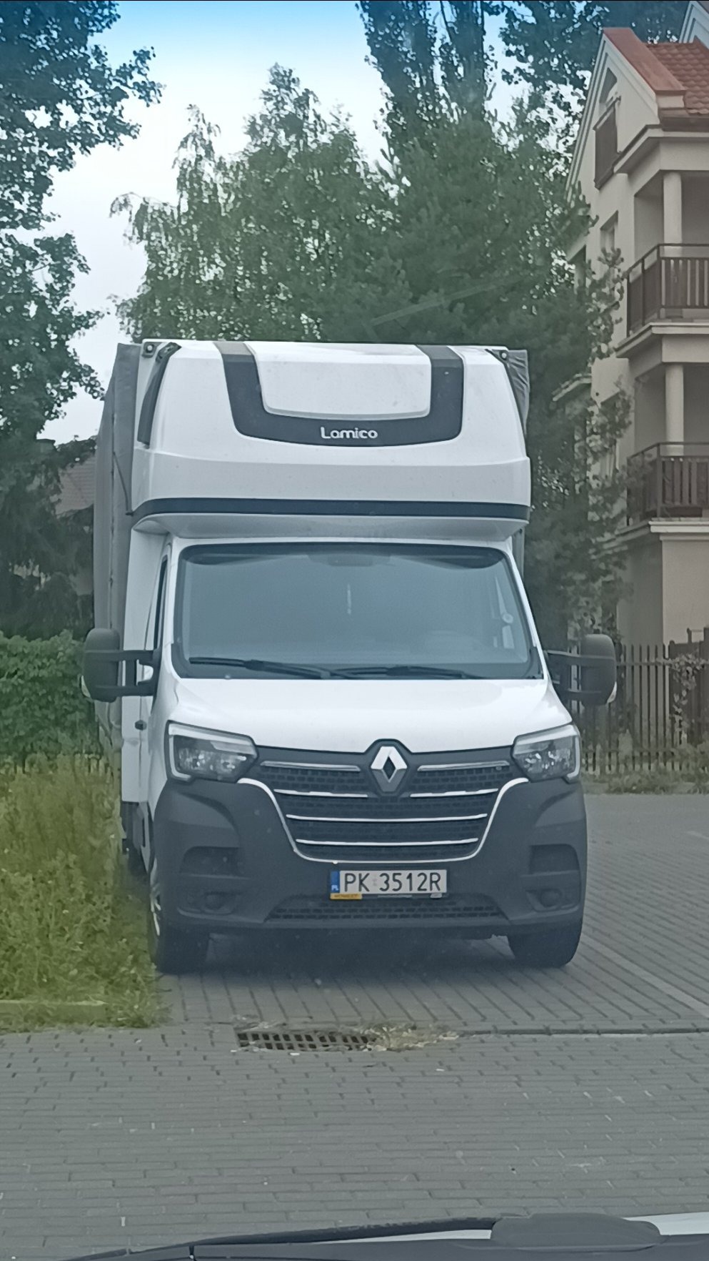 Biały bus Renault Master z nadbudówką Lamico, zaparkowany na brukowanej ulicy, widok z przodu, tablica rejestracyjna PK 3512R.