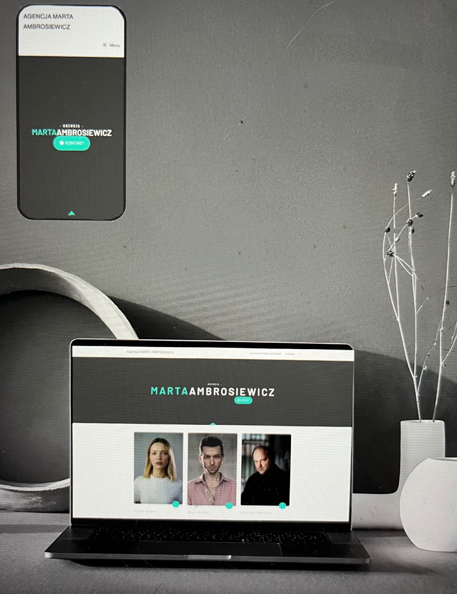 Ekran laptopa wyświetlający stronę internetową agencji Marta Ambrosiewicz, obok smartfon z widokiem mobilnej wersji tej samej strony, minimalistyczne tło z dekoracyjnym wazonem.