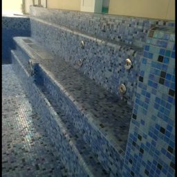 Usługi wykończeniowe - Wykończone schody do basenu z mozaiką w odcieniach błękitu i szarości, z dyszami hydromasażu.