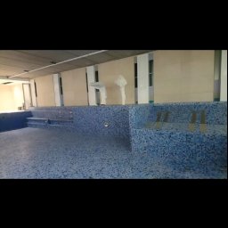 Usługi wykończeniowe - Niebieska mozaika w basenie w trakcie prac wykończeniowych, widoczne zabezpieczone folią elementy wyposażenia.