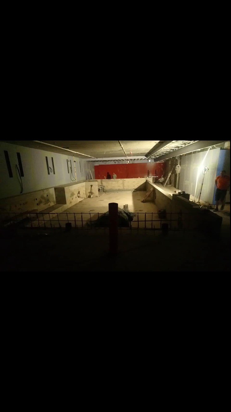 Wnętrze w trakcie prac przygotowawczych do remontu łazienki: surowe ściany, widoczne instalacje, częściowo wykończona podłoga, narzędzia w tle.