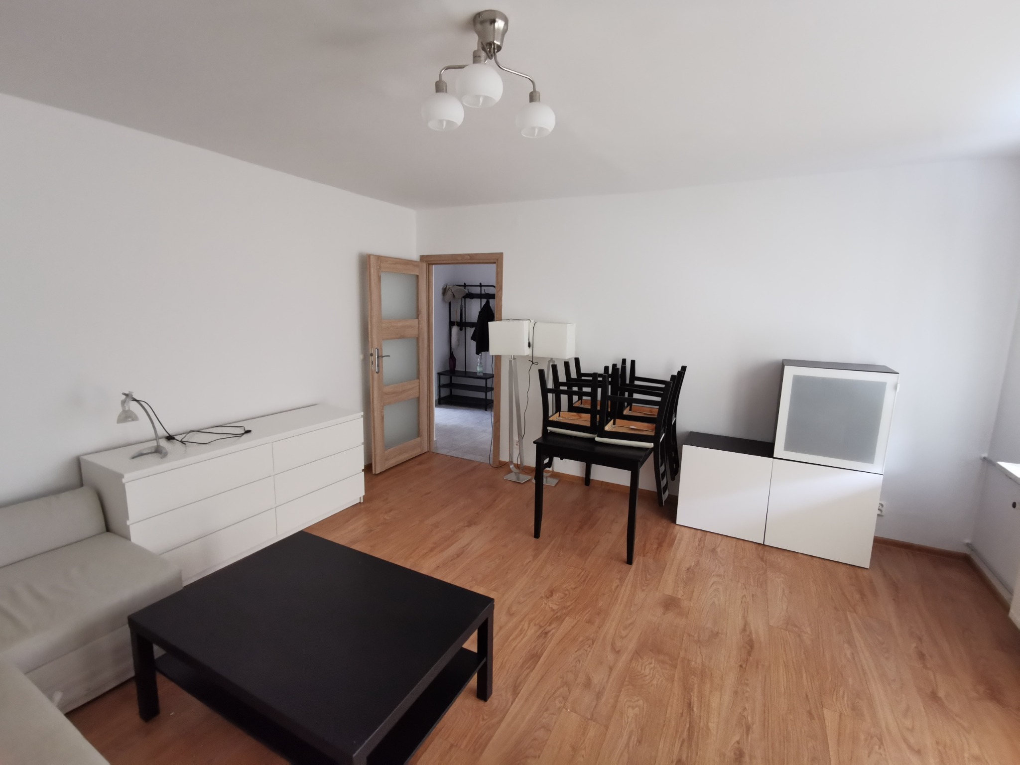 Puste, jasne mieszkanie po odświeżeniu ścian, z meblami ustawionymi na środku pokoju, gotowe do dalszej aranżacji.