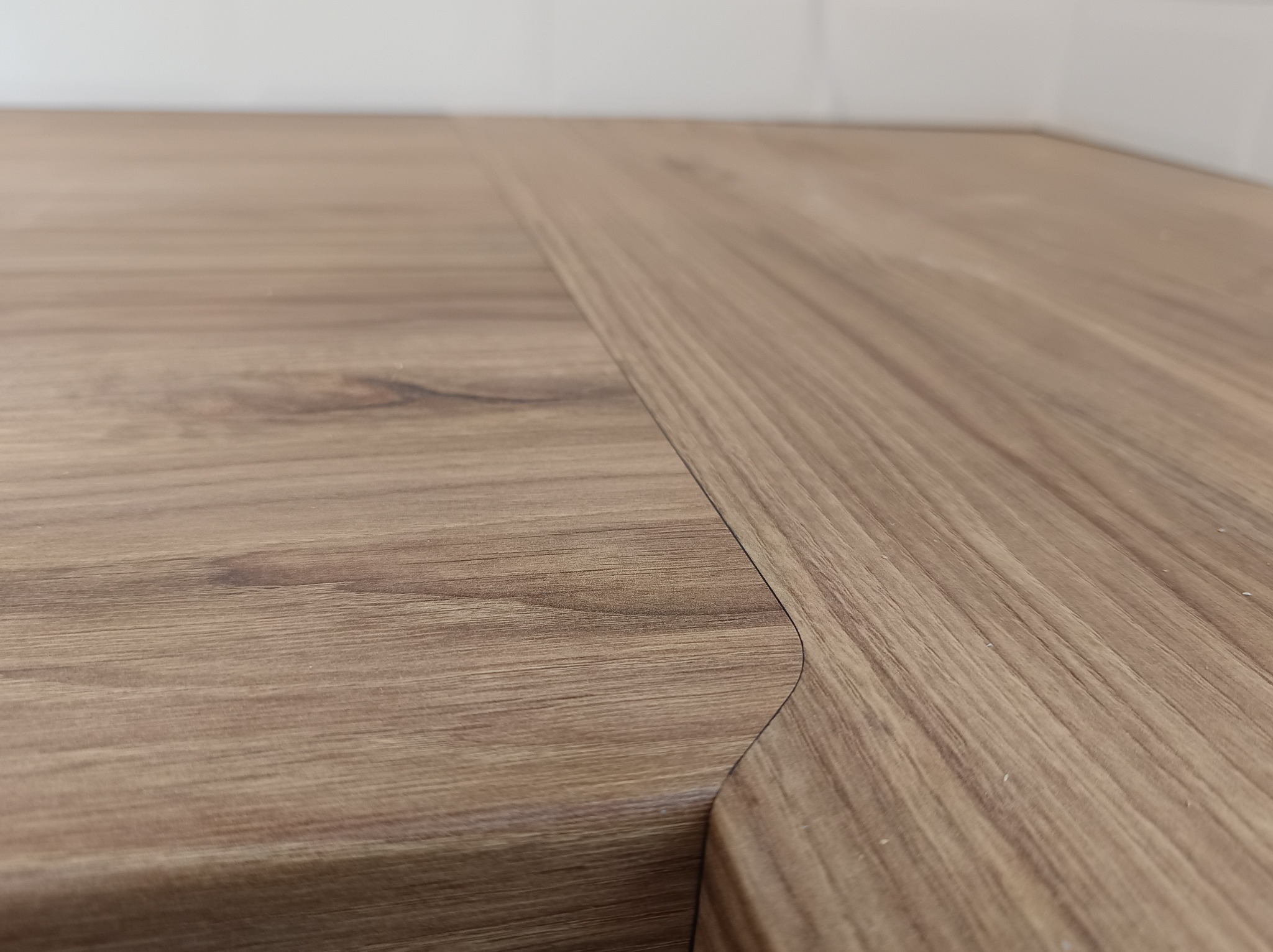 Połączenie dwóch blatów kuchennych o drewnopodobnym wzorze, widoczne delikatne zaokrąglenie krawędzi jednego z elementów.