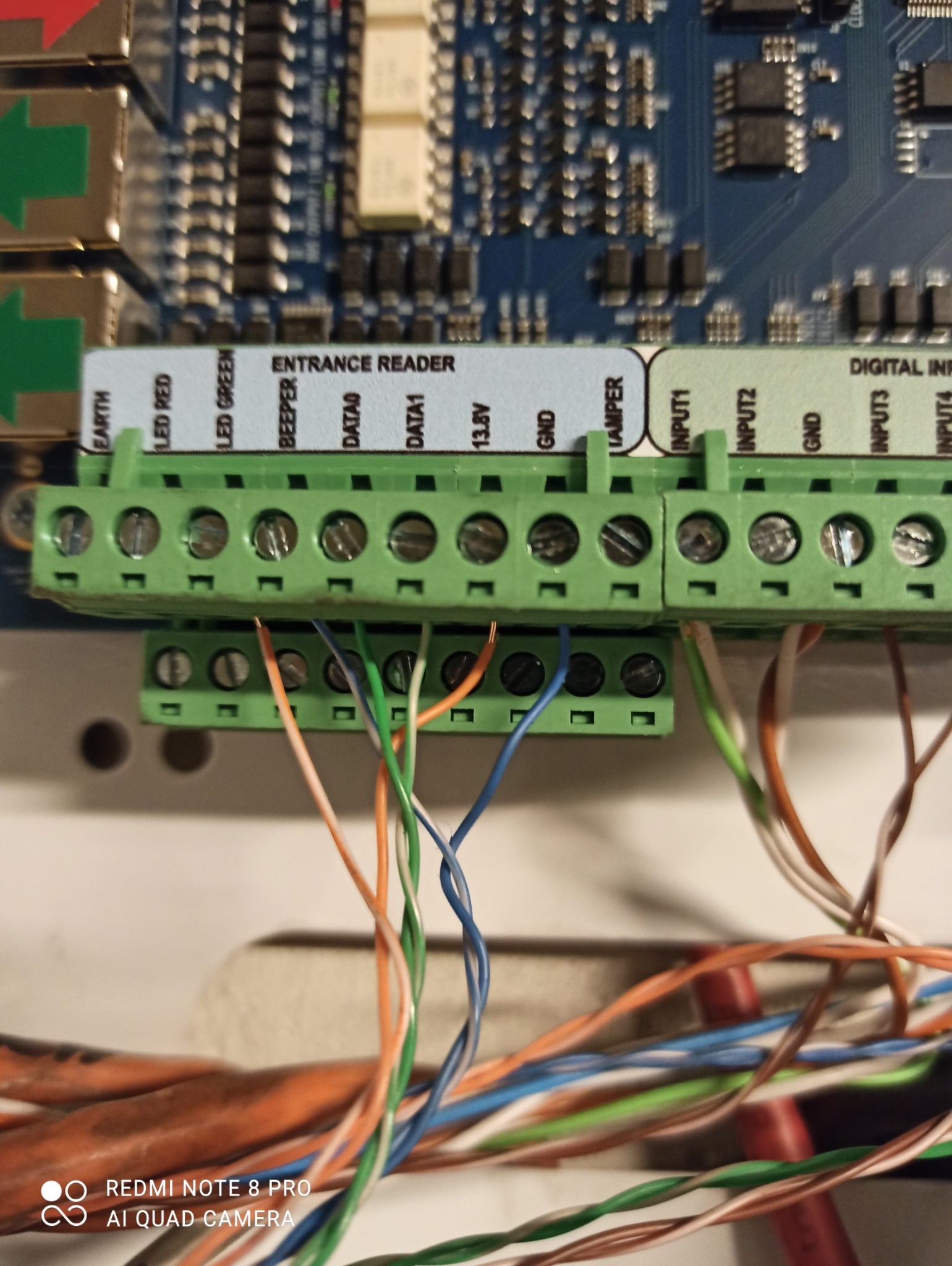 Szczegółowe ujęcie z bliska podłączenia przewodów do zielonych listew zaciskowych na płytce elektronicznej Entrance Reader z widocznymi opisami wejść/wyjść