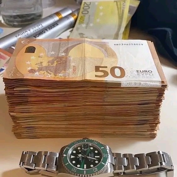 Stos banknotów 50 euro, zegarek Rolex Submariner z zielonym bezelem, dwa cygara Romeo y Julieta oraz banknot 200 euro w tle.