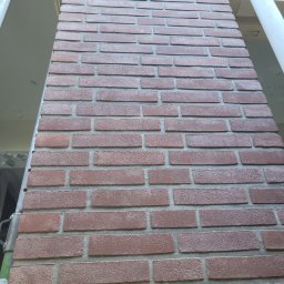 Firma Produkcyjno-Usługowa Przemysław Moskała - Wykończony komin obłożony cegłą klinkierową w odcieniach czerwieni i brązu, widoczny z dołu, z fragmentami rusztowania po bokach.