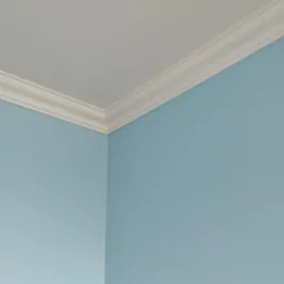 Ściana pomalowana na błękitno z białym, dekoracyjnym wykończeniem sufitu. Widoczny róg pokoju, gładka powierzchnia ściany i precyzyjne połączenie elementów.
