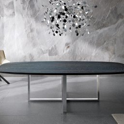 Drewbetex - Nowoczesny stół z ciemnym, owalnym blatem z drewna i metalowymi nogami, otoczony krzesłami w odcieniach beżu, a nad nim designerski żyrandol, na tle marmurowej ściany.