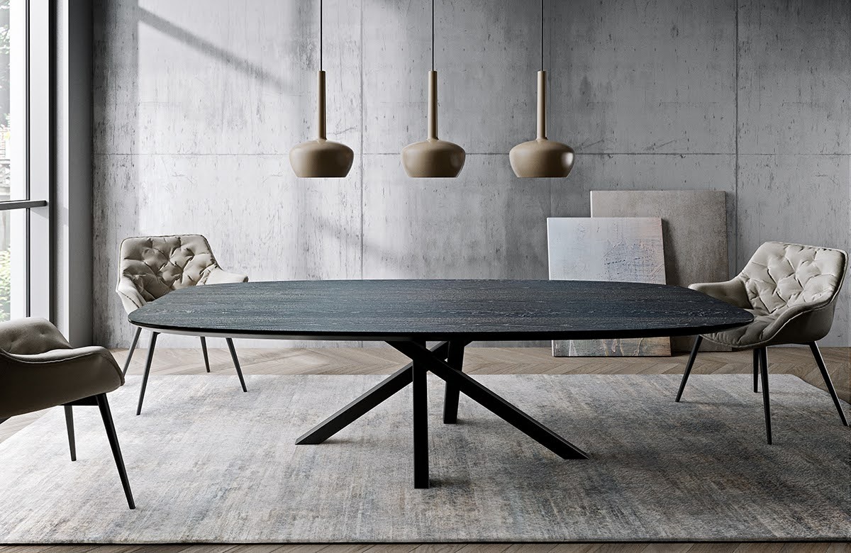 Stylowa jadalnia z owalnym blatem stołu w ciemnym odcieniu, wspartym na geometrycznej, czarnej podstawie. Nad stołem wiszą trzy identyczne, beżowe lampy. W tle betonowa ściana i dwa obrazy...