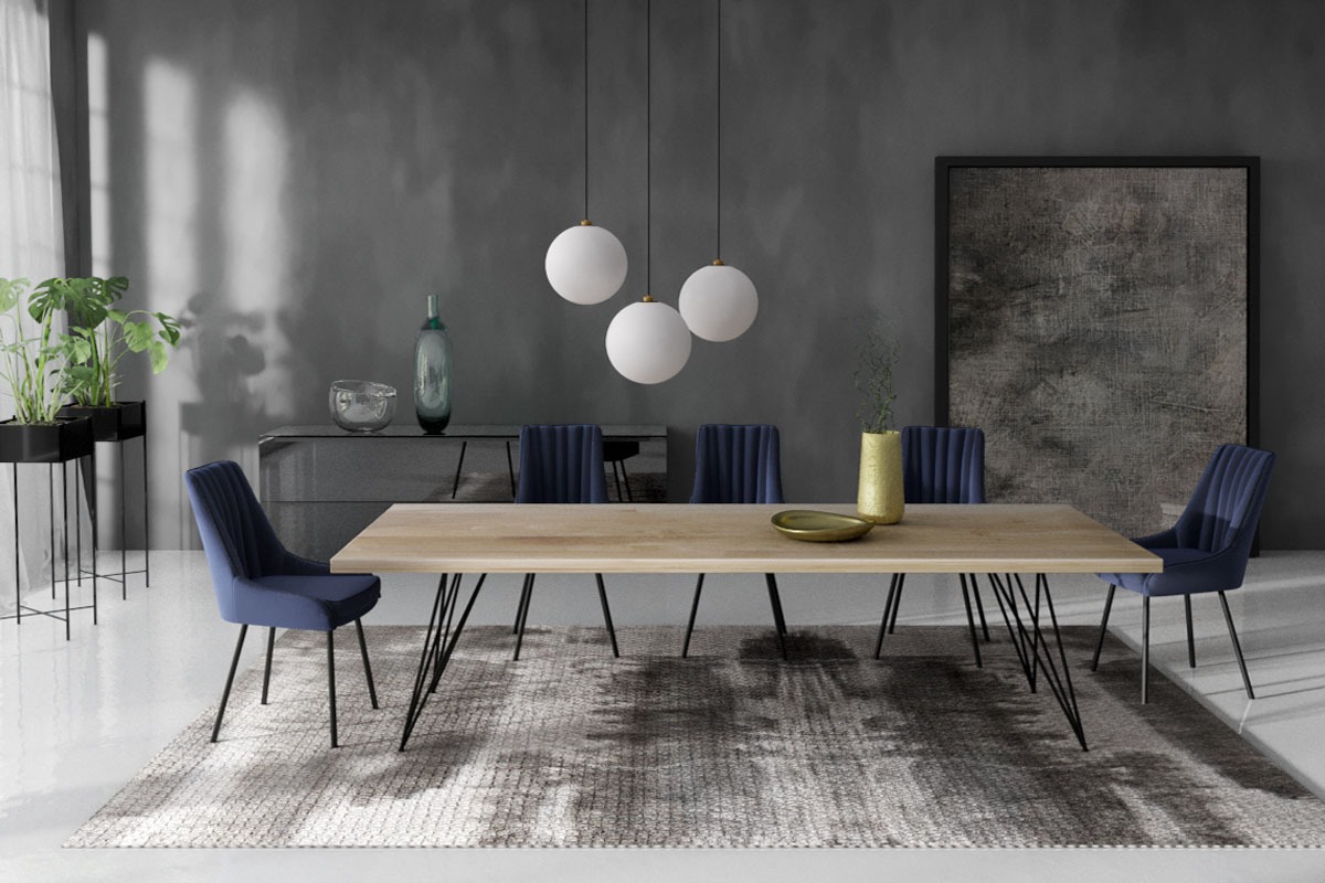 Jadalnia w odcieniach szarości i granatu: stół z blatem z jasnego drewna na czarnych, metalowych nogach, otoczony granatowymi krzesłami, na wzorzystym dywanie, oświetlony trzema białymi, kulistymi...