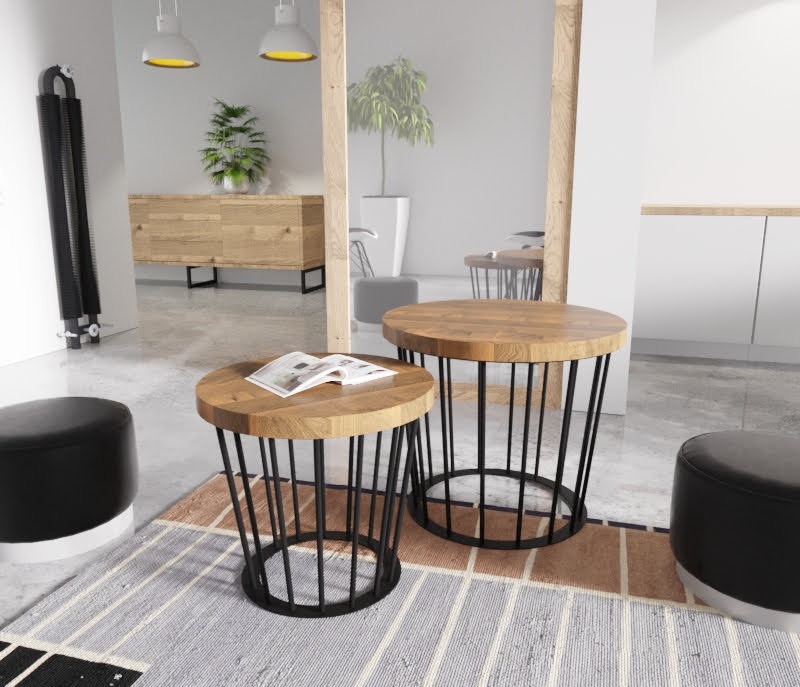Dwa okrągłe stoliki kawowe z drewnianymi blatami i czarnymi, metalowymi podstawami w kształcie koszy, ustawione na wzorzystym dywanie w nowoczesnym salonie z drewnianą komodą i roślinami w tle.