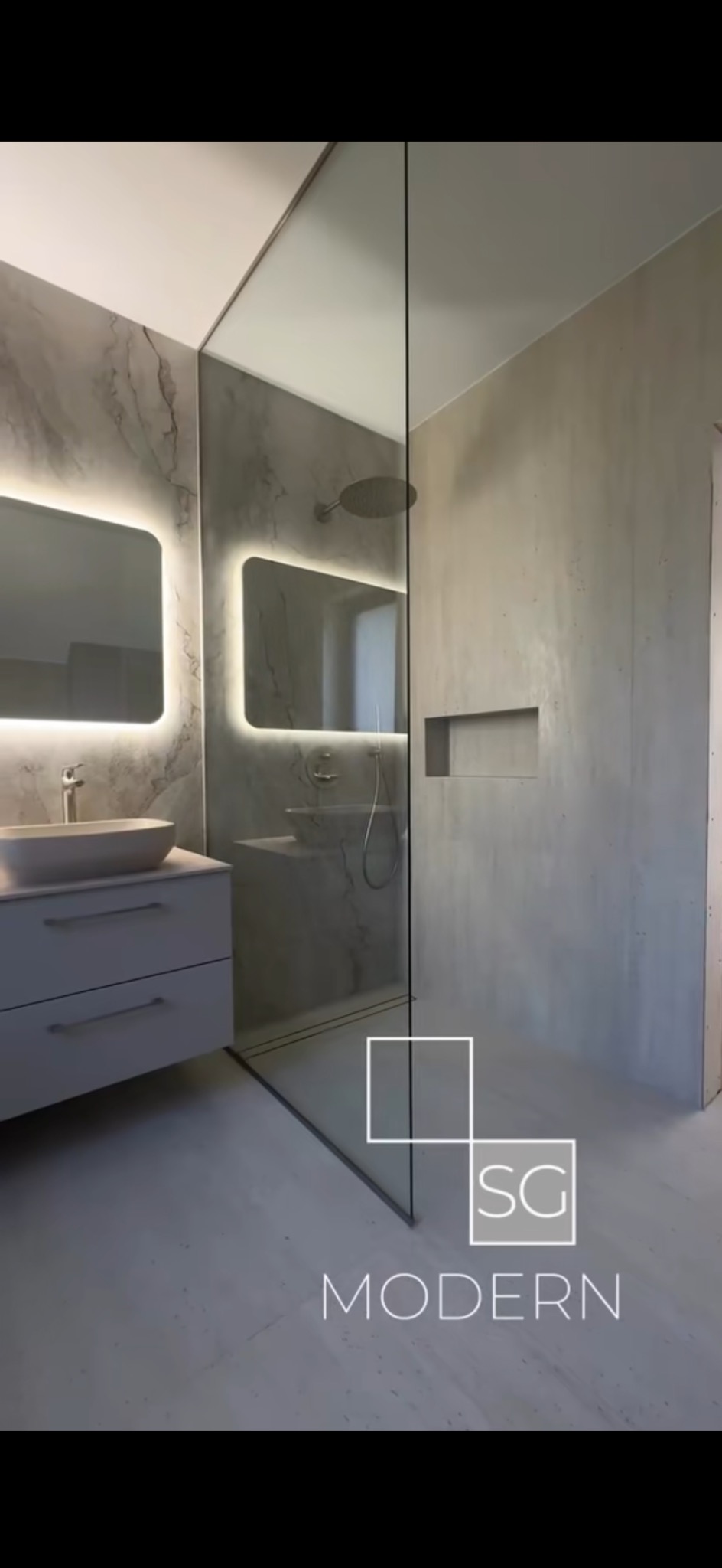 Nowoczesna łazienka z kabiną prysznicową typu walk-in, umywalką nablatową i podświetlanym lustrem. Minimalistyczny design, szare płytki imitujące marmur.
