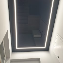 Tom-Kaj - Czarny, lustrzany sufit z kwadratowym oświetleniem LED w nowoczesnym wnętrzu, widok z dołu.