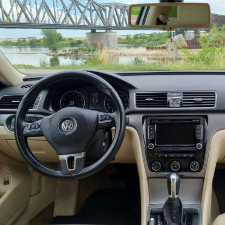 Wnętrze samochodu marki Volkswagen z widokiem na most i rzekę w tle, uchwycone z perspektywy kierowcy.