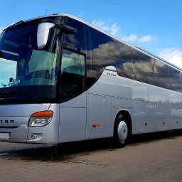 M-Turist - Srebrny autokar Setra S419GT-HD zaparkowany na zewnątrz, z odbiciem chmur w szybach i przyczepą z reklamą w tle.