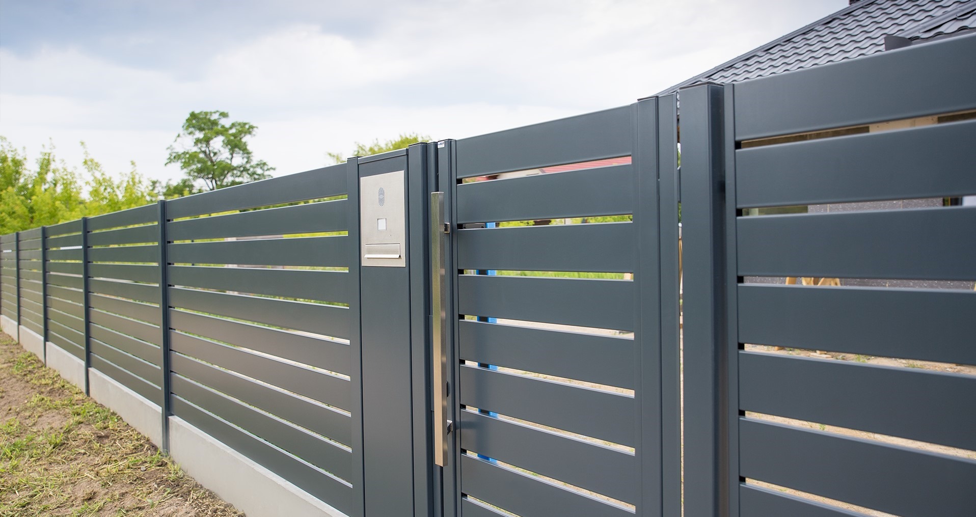 Nowoczesne, poziome ogrodzenie metalowe w kolorze grafitowym z furtką i skrzynką na listy, zrealizowane w Wiązownie.