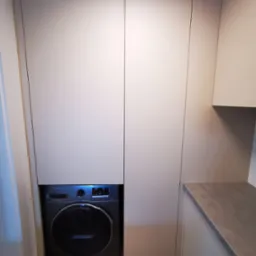 Pralka Samsung zabudowana w szafie z jasnymi frontami na wymiar, widoczny fragment blatu.