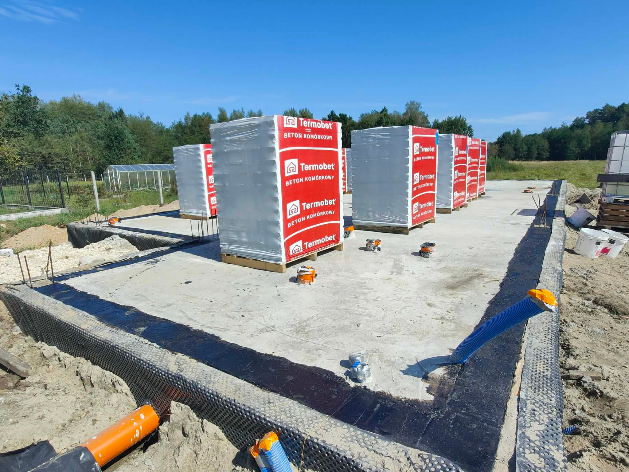 Fundamenty domu jednorodzinnego z izolacją, przygotowane do dalszych prac murarskich. Widoczne bloczki z betonu komórkowego Termobet.