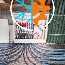 ACTIV KRZYSZTOF LESZCZYŃSKI - Niebieskie rury ogrzewania podłogowego Kan Therm Blue Floor ułożone na folii z siatką, z rozdzielaczem w białej szafce. Widoczne drewniane belki stropu.