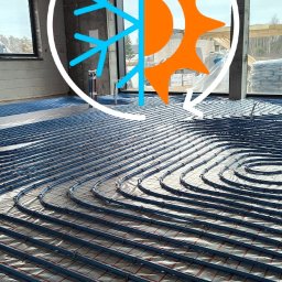 ACTIV KRZYSZTOF LESZCZYŃSKI - Niebieskie rury ogrzewania podłogowego ułożone na folii z czerwoną kratką w surowym wnętrzu budynku. W tle okno i materiały budowlane. Grafika słońca i śnieżynki.