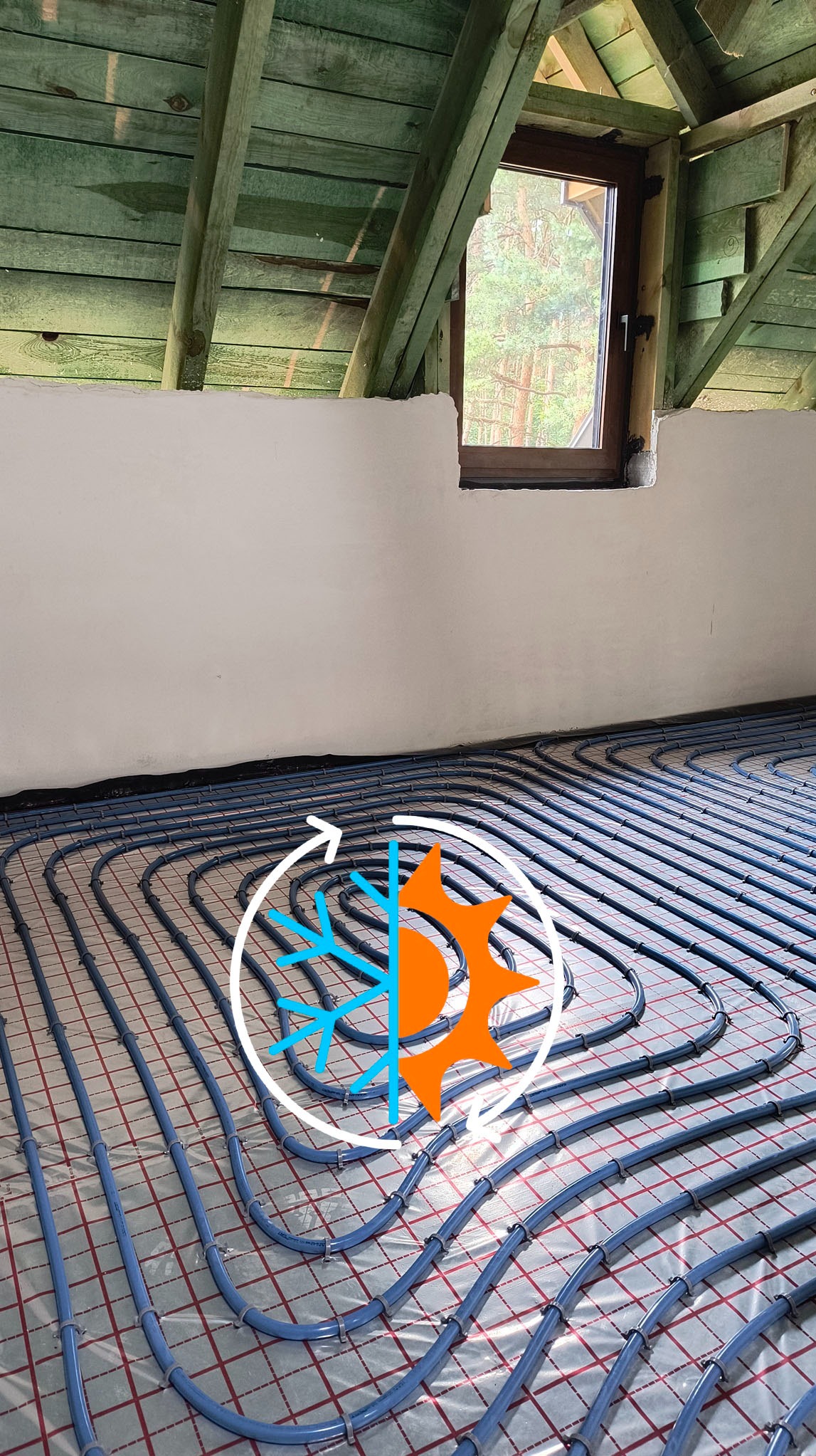 Niebieskie rury ogrzewania podłogowego na folii w poddaszu, widok z góry. Grafika słońca i śnieżynki symbolizuje regulację temperatury. Okno w tle.