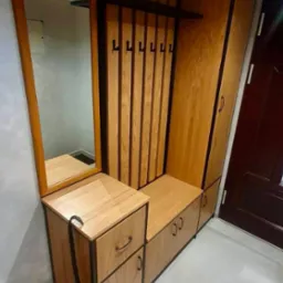 Funkcjonalna zabudowa przedpokoju z lustrem, w stylu loft, z drewnianymi elementami i czarnymi detalami, w tym wieszakami i obramowaniami.