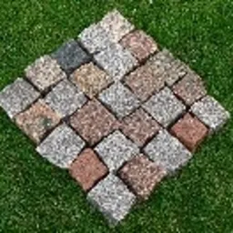 Ułożony z kostek wzór rombu na tle trawy. Kostki w odcieniach szarości, brązu i beżu, o nieregularnej fakturze. Widoczne drobne nierówności i szczeliny między kostkami.