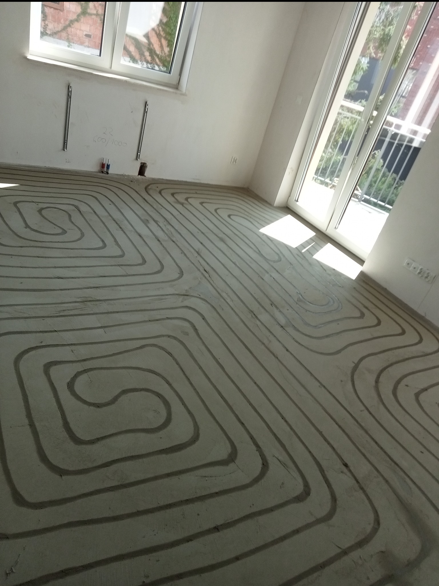 Wnętrze w Bojanowie z widocznym systemem ogrzewania podłogowego w trakcie instalacji, rurki ułożone w pętle na wylewce, przygotowane do zalania betonem.