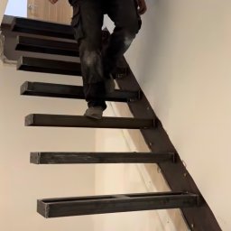 Kul-Spaw - Montaż ażurowych schodów z metalowych profili; widoczny pracownik w ubraniu roboczym w trakcie wchodzenia po nieukończonej konstrukcji.