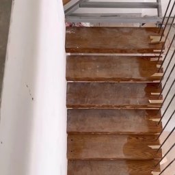 Kul-Spaw - Wewnętrzne schody z drewnianymi stopniami i metalową konstrukcją nośną, widok z góry na etapie montażu poręczy.