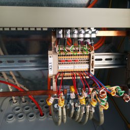 ELEKTOM Tomasz Czopek - Panel sterowania z precyzyjnie ułożonymi przewodami oznaczonymi numerami, podłączonymi do listwy zaciskowej. Widoczne szyny montażowe i elementy mocujące.