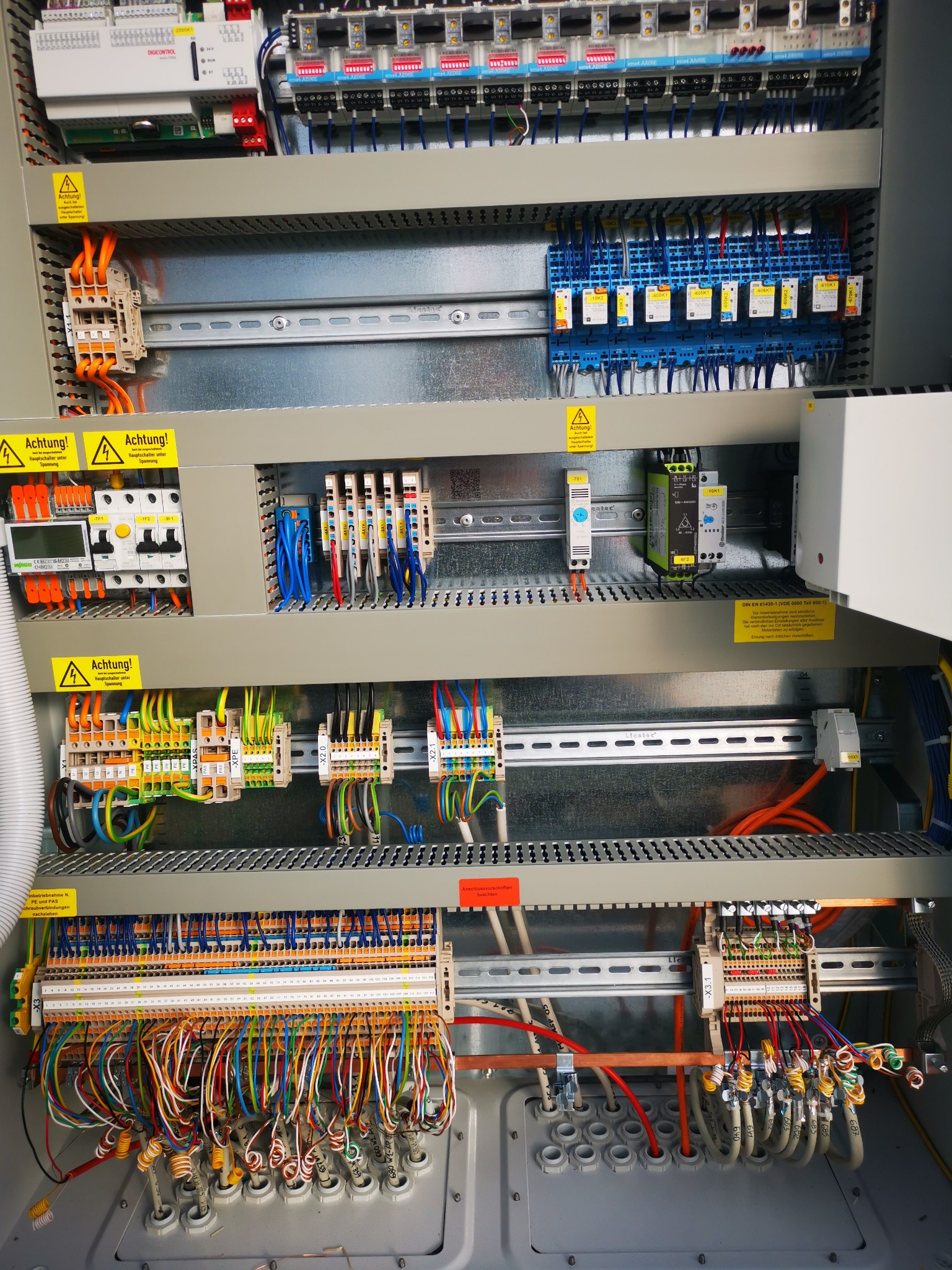 Rozbudowana szafa sterownicza z licznymi przewodami, modułami i zabezpieczeniami. Widoczne oznaczenia, listwy zaciskowe i elementy montażowe. Precyzyjne i uporządkowane okablowanie.