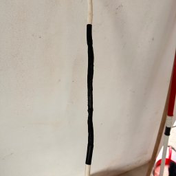 INSTALATORSTWO ELEKTRYCZNE Artur Marański - Biały przewód elektryczny z czarną taśmą izolacyjną na tle jasnej ściany z widocznymi zabrudzeniami i elementami wyposażenia wnętrza.