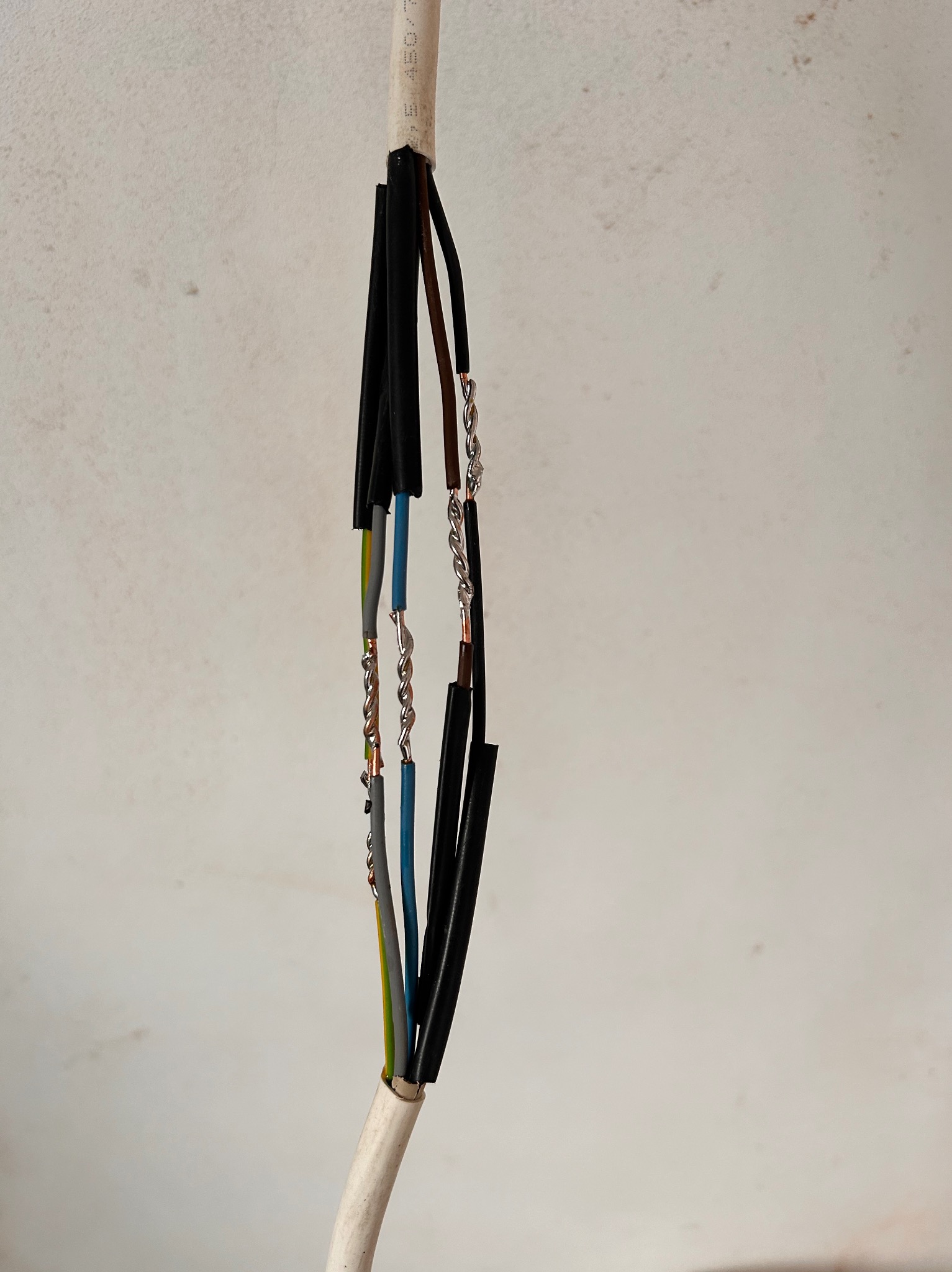 Połączenie przewodów elektrycznych z izolacją i skręconymi żyłami, widoczne kolory izolacji i oznaczenia na kablu.