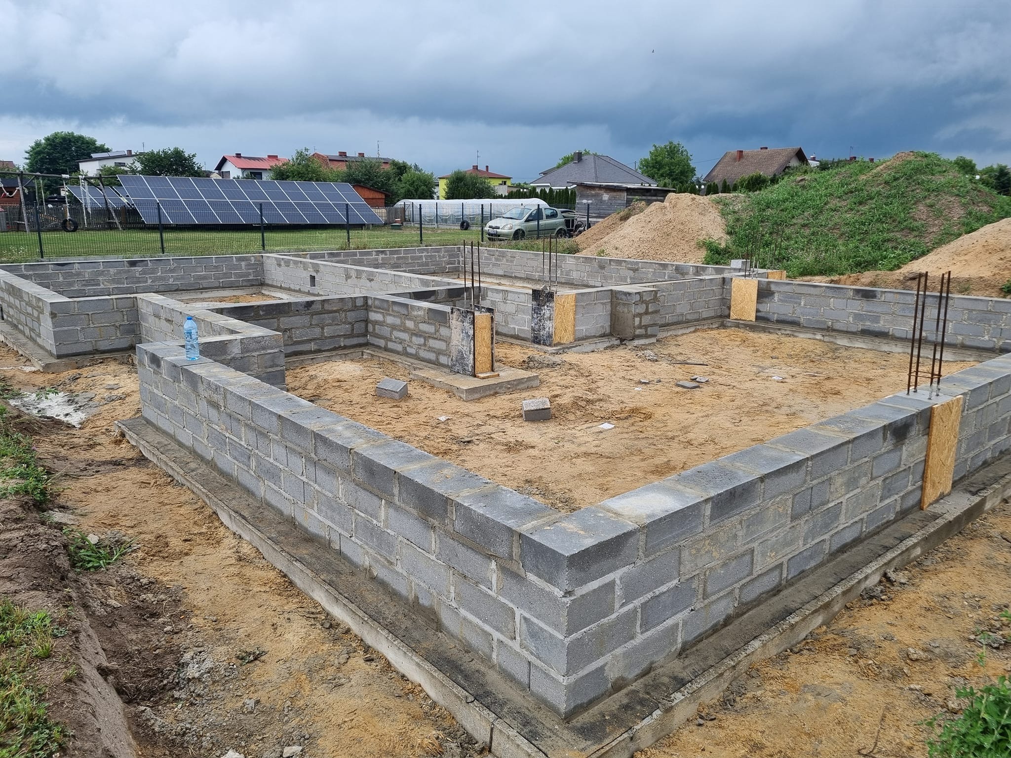 Fundamenty z bloczków betonowych, z wystającymi prętami zbrojeniowymi, Łódź, widoczne szalunki i butelka wody na murze.