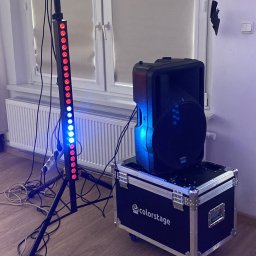 Dmytro Sokolov - Sprzęt nagłośnieniowy i oświetleniowy: kolumna głośnikowa na skrzyni Colorstage, obok listwa LED na statywie, w tle okno i apteczka pierwszej pomocy.