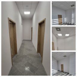 F.U.H ALFA - Korytarz biurowy z szarymi płytkami podłogowymi, białymi ścianami i trzema drewnianymi drzwiami, widok z perspektywy długiego korytarza oraz detale wykończenia ścian i sufitu z kratkami...