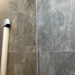 ABX BUDOWNICTWO SPÓŁKA Z OGRANICZONĄ ODPOWIEDZIALNOŚCIĄ - Szare, matowe płytki imitujące kamień na ścianie, pionowy odpływ liniowy z chromowaną nakładką po lewej stronie.